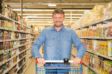 man pushing shopping trolly in the supermarket aisles, shopping concept