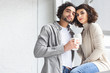 © LIGHTFIELD STUDIOS - young couple holding cups of coffee and looking at camera at home