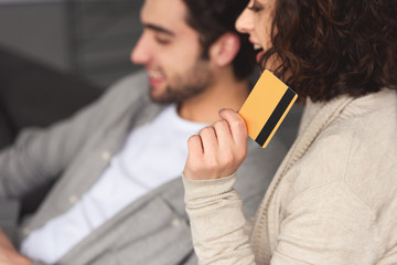 Poster - girlfriend holding credit card and looking away at home