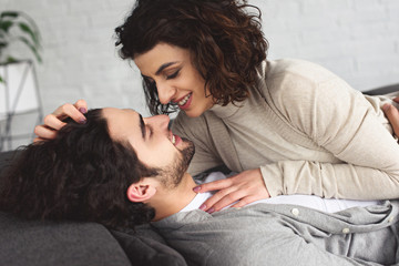 Poster - young couple lying on sofa and looking at each other at home