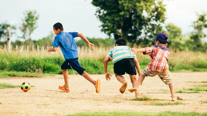 An action sport picture of a group of kid playing soccer football for exercise in community rural area 