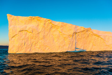 Wall Mural - yacht's shadow on a iceberg. sunrise in greenland