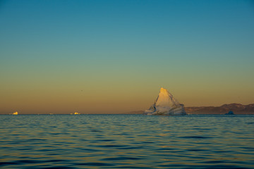 Wall Mural - sunrise in fjord. light on iceberg