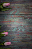 Fototapeta Tulipany - Border from bright pink tulips flowers on black wooden background. Selective focus, place for text