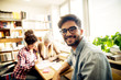 © Dusan Petkovic - Portrait of a young joyful male student learning on a library desk on which two female students are studying in a background.