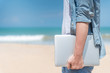 Male hand holding laptop on the beach, working outdoor in summer season, digital nomad man lifestyle concepts