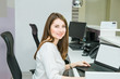 Portrait of smiling skilled administrative manager working on laptop with white empty screen in office satisfied with occupation, young female receptionist. Selective focus, space for text.
