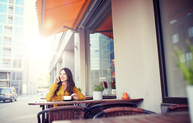 Canvas Print - communication, technology, leisure and people concept - happy young woman or teenage girl calling on smartphone and drinking cocoa at city street cafe terrace