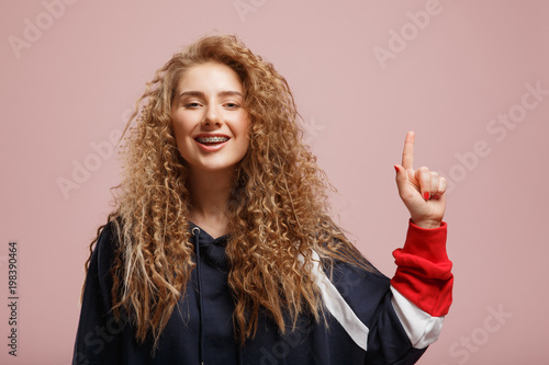 Girl With Curly Hair And Braces On Her Teeth Smiles Broadly Looks