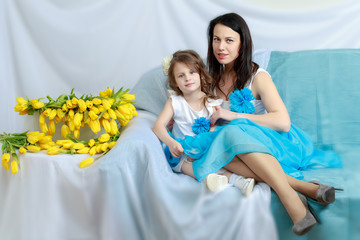 Wall Mural - Mom and daughter on the sofa with a bouquet of flowers.