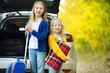 © MNStudio - Two adorable girls with a suitcase going on vacations with their parents. Two kids looking forward for a road trip or travel. Autumn break at school.