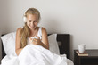 © AnastazjaSoroka - Happy morning. Young woman listen music in white bed.