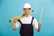 Happy male builder in protective helmet holding level tool