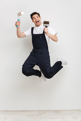 Wall Mural - Full length image of Screaming male builder jumping