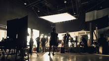 Behind The Scenes Of Silhouette People Working In Big Production Studio With Professional Set And Lighting For Making Movie Film Or Video Commercial.