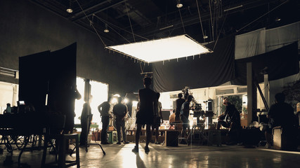 behind the scenes of silhouette people working in big production studio with professional set and li