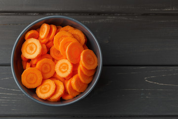 Sliced carrots in a bowl on black background