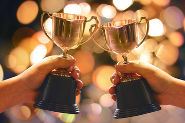 Wall Mural - two winners show trophy with abstract bokeh light background