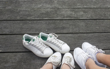 Two pairs of white sneakers waiting for the owner of the third