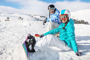 Canvas Print - Couple of snowboarders on ski piste at snowy resort. Winter vacation