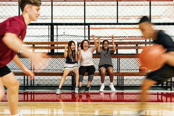 Wall Mural - Teenage girls cheering the boys playing basketball