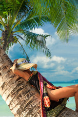 Woman on the tropical beach sitting on a tree