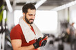 © proimagecontent - Bearded muscular man wears red t-shirt using smartphone in the gym