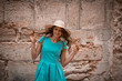 © Елена Кравчук - Funny young woman in hat and blue dress, looking camera, smiling, on stone street background