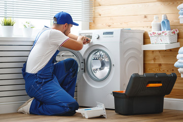 working man   plumber repairs  washing machine in   laundry.