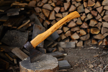 The ax in the stump on the background of firewood