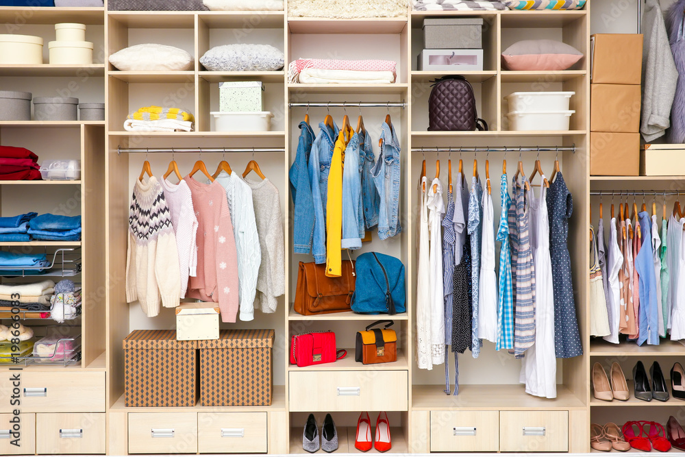 Large wardrobe with female clothes and accessories in dressing room