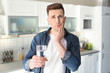 © New Africa - Young man with sensitive teeth and glass of cold water in kitchen
