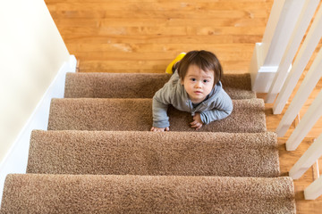 Wall Mural - Toddler boy climbing a staircase in his house