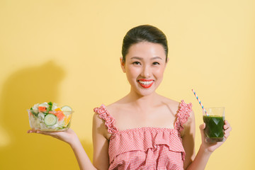 Elegant pretty slim woman holding a bowl of salad and a glass of detox.