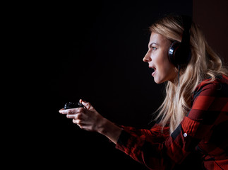 Wall Mural - girl gamer in headphones and with a joystick enthusiastically playing on the console