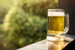 Drinking Beer in Summer Concept. Glass of Beer on Balcony. Natural Sunlight and Tree as background, Warm Tone