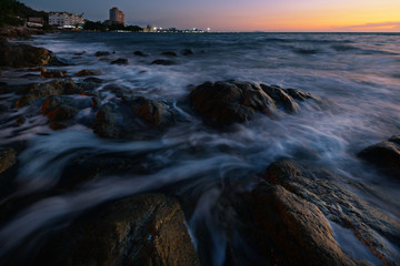 Wall Mural - wave at the sea on the rock with sunset sky