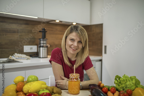 Plakat Młoda kobieta pije smoothie w kuchni