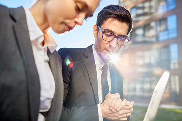 Sticker - Elegant businessman in eyeglasses and suit and his colleague discussing papers during outdoor meeting on sunny day