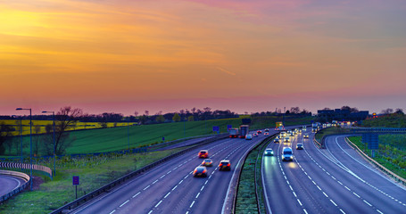 Colourful sunset at M1 motorway near Flitwick junction with blurry cars in United Kingdom