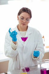 Wall Mural - young woman scientist working with laboratory glassware with different colors liquid in a laboratory