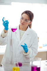 Wall Mural - young woman scientist working with laboratory glassware with different colors liquid in a laboratory