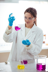 Wall Mural - young woman scientist working with laboratory glassware with different colors liquid in a laboratory