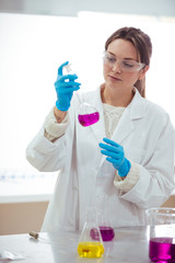 Wall Mural - young woman scientist working with laboratory glassware with different colors liquid in a laboratory