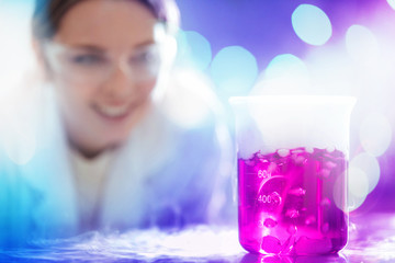 Wall Mural - young woman scientist working with laboratory glassware with pink liquid and white smoke in a labora