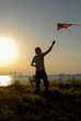© ruslanshug - silhouette of active young man in cap launching colorful kite flying in air at summer sunset near sea