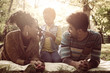 © Mladen - Smiling African American parents lying down in nature and talking with little daughter.