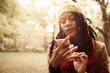© Mladen - Smiling Africana American girl standing in park and typing on mobile phone.