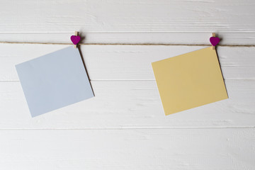 Wall Mural - Yellow and blue memo sheets fastened with a decorative pins on a white wooden board.