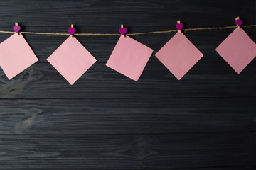 Wall Mural - Pink memo sheets fastened with a decorative pin on a dark blue wooden board.